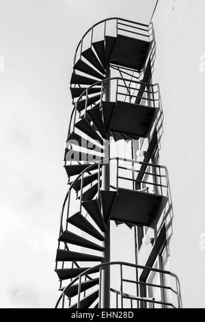 Abstrakt Architektur Fragment, alte Outdoor-Metall-Spirale-Leiter an der Wand, schwarz / weiß-Foto Stockfoto