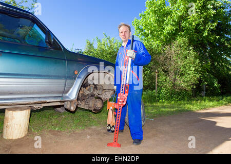 Der Mann in der Arbeit Overall ändert eine Rad Stockfoto