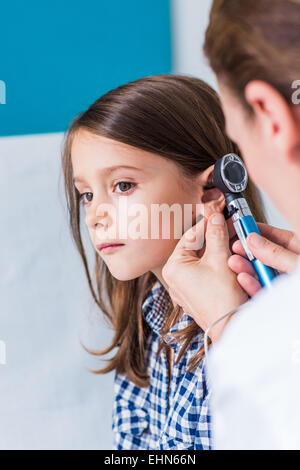 Arzt untersucht die Ohren von einem 7 Jahre alten Mädchen mit einem Otoskop. Stockfoto