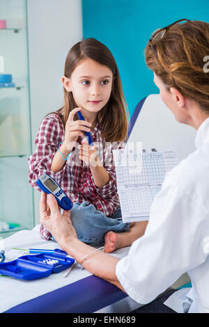 Diabetische 7-Year-Old Girl hören von ihrem Arzt erklären, wie man eine Art von Insulin Spritze verwenden. Stockfoto