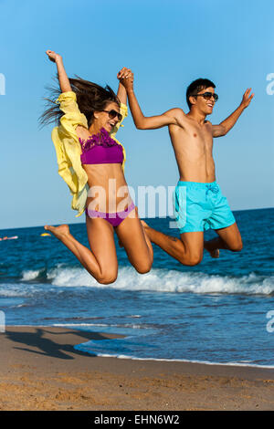 Dynamische Teen paar in Badesachen am Strand springen. Stockfoto