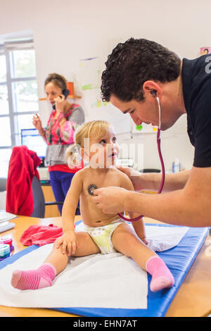 Arzt untersucht ein 2 Jahre alten Mädchen mit einem Stethoskop, Mutter und Kinder-und Jugendhilfe, Charente, Frankreich. Stockfoto