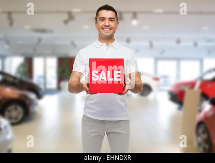 glücklicher Mann mit Verkauf Seufzer über Auto Show Hintergrund Stockfoto