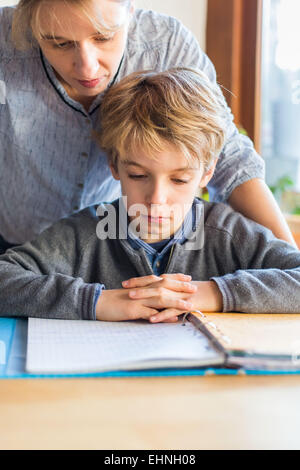 8 Jahre alter Junge Hausaufgaben mit seiner Mutter. Stockfoto