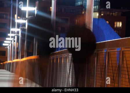 Zwei Männer, die zu Fuß über eine Fußgängerbrücke in der Nacht Stockfoto