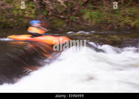 Kajakfahrer Eingabe Whtewater Stromschnellen River Dart UK mit Motion blur Stockfoto