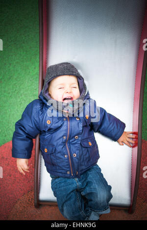 18 Monate altes Baby junge auf einer Folie auf einem Spielplatz. Stockfoto