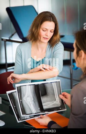 Herr Doktor, Prüfung und Kommentierung des Patienten Ellenbogen Röntgen. Stockfoto