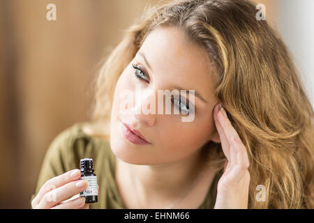 Frau Anwendung ätherisches Öl auf ihre Tempel. Stockfoto