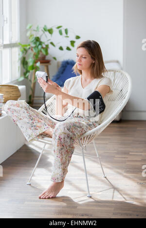 Frau, die ihren Blutdruck mit ein tragbares Blutdruckmessgerät. Stockfoto