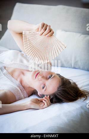 Frau, die ihr Gesicht mit einem Ventilator zu kühlen. Stockfoto