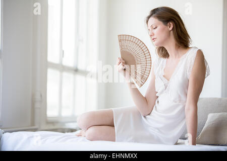 Frau, die ihr Gesicht mit einem Ventilator zu kühlen. Stockfoto