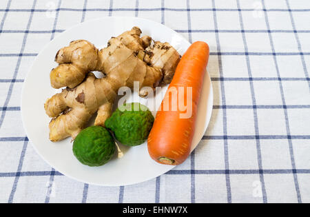 Zwei Kaffir Limonen mit Galgant und Karotten auf weißen Teller auf quadratischen Hintergrund platziert Stockfoto