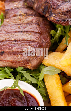 Gesunde Platte mit gemischtem Fleisch einschließlich gegrilltes Steak, knusprig Panierter Hühner- und Rindfleisch auf einem Bett aus frischen grünen grünen gemischten sa Stockfoto