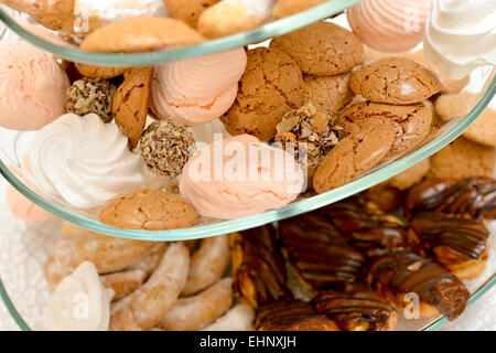 Kekse, Marshmallows, Eclair, Schokokugeln mit Nüssen auf Glasauflage gelegt Stockfoto