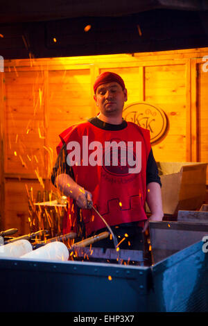 Ein Mann kocht Kurtos Kalacs auf einem Weihnachtsmarkt, Budapest, Ungarn Stockfoto