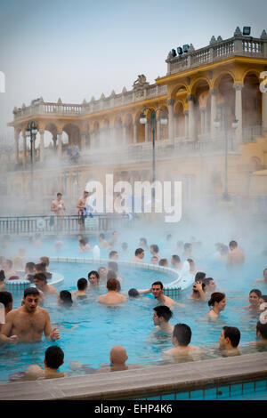 Touristen und Einheimische genießen die Széchenyi-Thermen an einem kalten Wintertag, Budapest, Ungarn Stockfoto