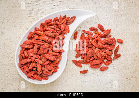 getrocknete Goji-Beeren in eine Träne geformt Bowl gegen rustikal weiß lackiertem Holz Stockfoto