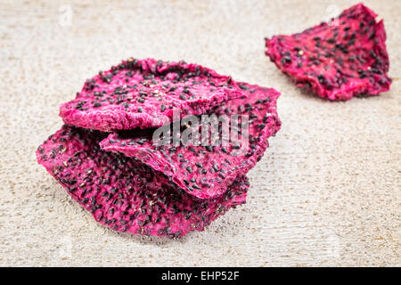 Scheiben von getrockneten roten Drachenfrucht gegen rustikal weiß lackiertem Holz Stockfoto