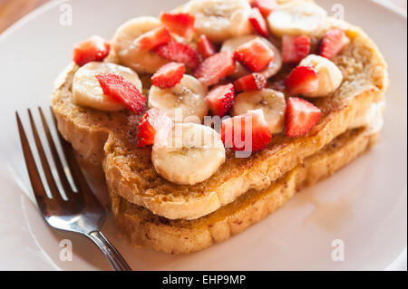 Zwei Scheiben French Toast mit in Scheiben geschnittenen Bananen und Erdbeeren an der Spitze Stockfoto