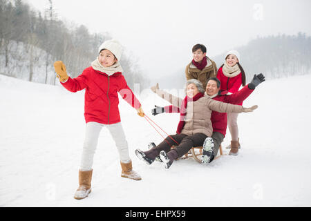 Glückliche Familie mit Schlitten im Schnee spielen Stockfoto