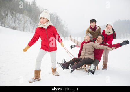 Glückliche Familie mit Schlitten im Schnee spielen Stockfoto