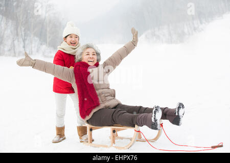 Enkelin drängen Großmutter auf Schlitten Stockfoto