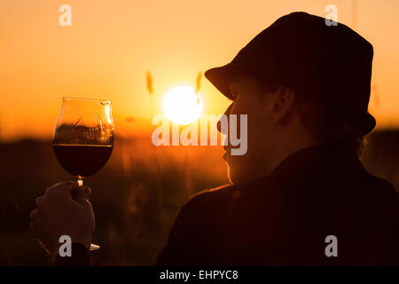 junger Mann trinkt Wein in den Sonnenuntergang Stockfoto