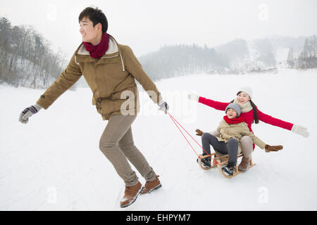 Glückliche Familie mit Schlitten im Schnee spielen Stockfoto