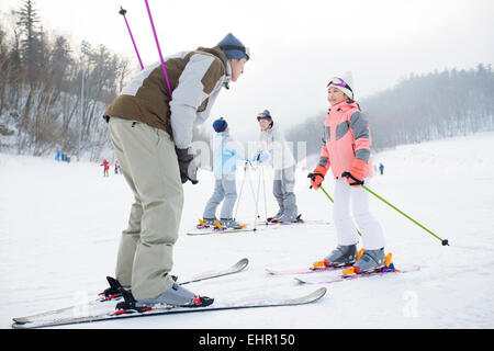 Junge Eltern, die Erziehung von Kindern zum Skifahren Stockfoto