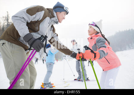 Junge Eltern, die Erziehung von Kindern zum Skifahren Stockfoto