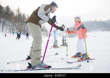 Junge Eltern, die Erziehung von Kindern zum Skifahren Stockfoto