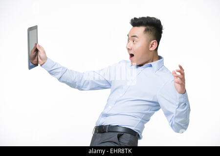 Junger Geschäftsmann hält digitale Tablet mit überrascht Ausdruck Stockfoto