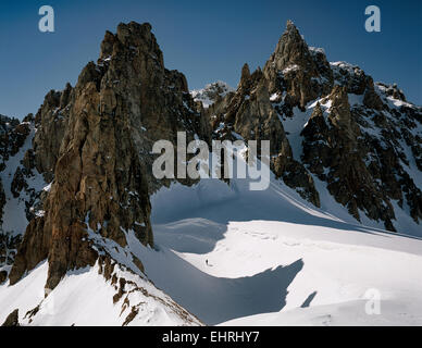 Einzelne Figur Spaziergänge im Schnee unter den Felsen im Alter Nielsen Gletscher, Tvillingerne, Ostgrönland Stockfoto