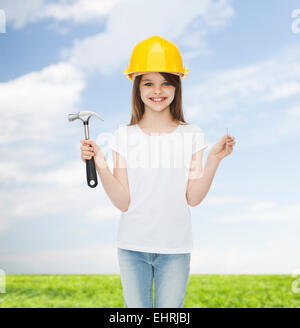 lächelnde Mädchen im Helm mit hammer Stockfoto