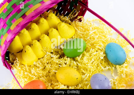 farbige Ostereier, gelben Küken und Süßigkeiten in einem Korb Stockfoto