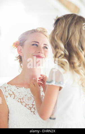Braut und Brautjungfer einander zugewandt und lächelnd Stockfoto