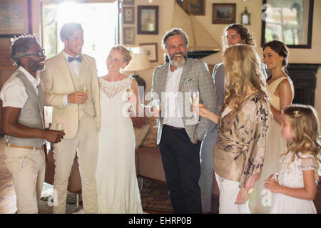 Junges Paar mit Gästen und Sektgläser bei Hochzeitsfeier Stockfoto