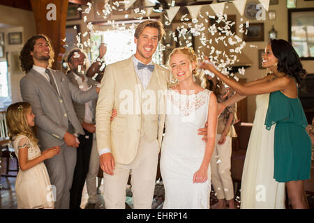 Porträt des Lächelns in fallenden Konfetti junges Paar stehen während der Hochzeitsfeier Stockfoto