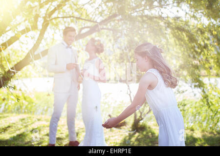 Braut, Bräutigam und Brautjungfer spielen mit Dekorationen im Hausgarten während der Hochzeitsfeier Stockfoto