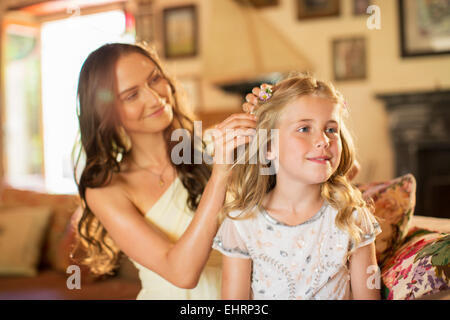 Brautjungfer hilft Mädchen mit Frisur im Wohnraum Stockfoto