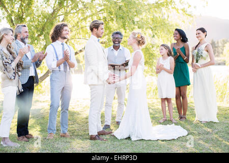 Junges Paar und Gäste während der Trauung im Hausgarten Stockfoto