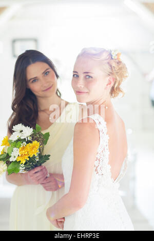 Porträt von Braut und Brautjungfer mit Blumenstrauß im Wohnraum Stockfoto