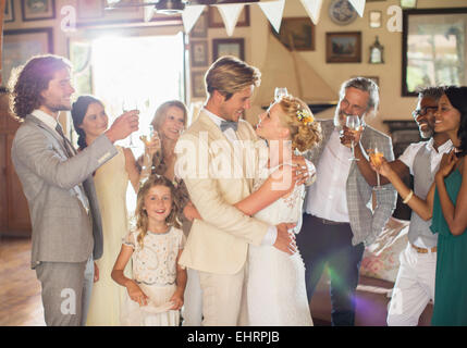 Bräutigam umarmen Braut während der Hochzeitsfeier im Wohnraum Stockfoto