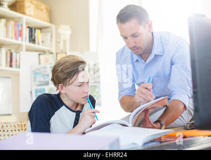 Vater Sohn im Teenageralter mit seinen Hausaufgaben zu helfen Stockfoto