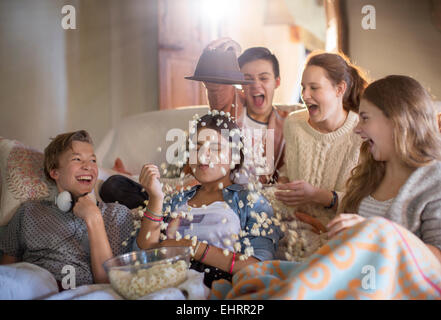 Gruppe von Jugendlichen werfen Popcorn auf sich sitzend auf sofa Stockfoto