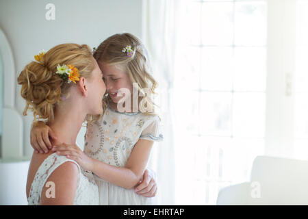 Braut und Brautjungfer einander zugewandt und lächelnd in Schlafzimmer Stockfoto