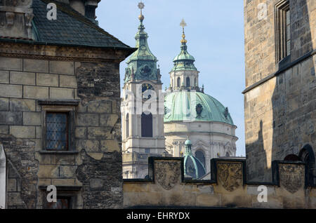 Nahaufnahme der Kuppel und Glockenturm der Kathedrale Sankt Nikolaus zwischen Türmen der Karlsbrücke auf der Seite der Kleinseite Stockfoto