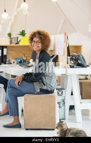 Junge lächelnde Frau am Schreibtisch Stockfoto