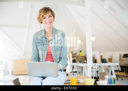 Büroangestellte mit Kaffee mit laptop Stockfoto